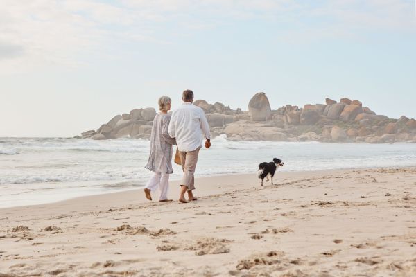 Retired couple walking with their dog along the beach